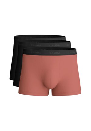 Drie herenboxers op een rij, voorste roestkleurig met zwarte tailleband, twee daarachter zwart met zwarte tailleband, merknaam zichtbaar op de band.