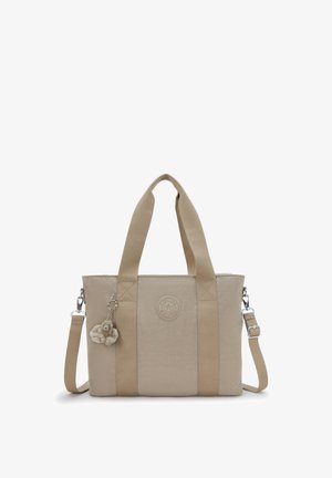 Borsa a mano beige con manici larghi in tessuto, tracolla removibile, toppa rotonda con logo e portachiavi con scimmietta in peluche attaccato.