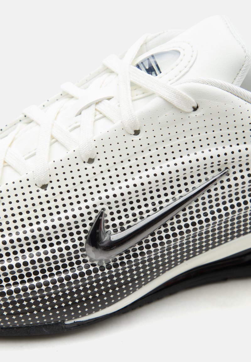 Zapato deportivo blanco con diseño degradado de puntos negros y logo Nike swoosh negro en el lateral, cierre de cordones y cuello acolchado.