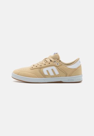 Beige skate shoes with a soft suede upper, white accents, perforated detailing, and a light rubber sole for grip and durability.