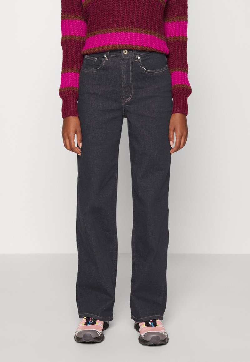 Mörka jeans med rak benmodell, utrustade med standardfickor och silverfärgad metalldetalj, kombinerade med en strukturerad tröja i magenta och brunt.