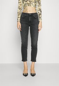 Svarta beskurna jeans med smal passform och fransad kant, kombinerade med en figurnära, mönstrad långärmad topp och spetsiga svarta klackar.