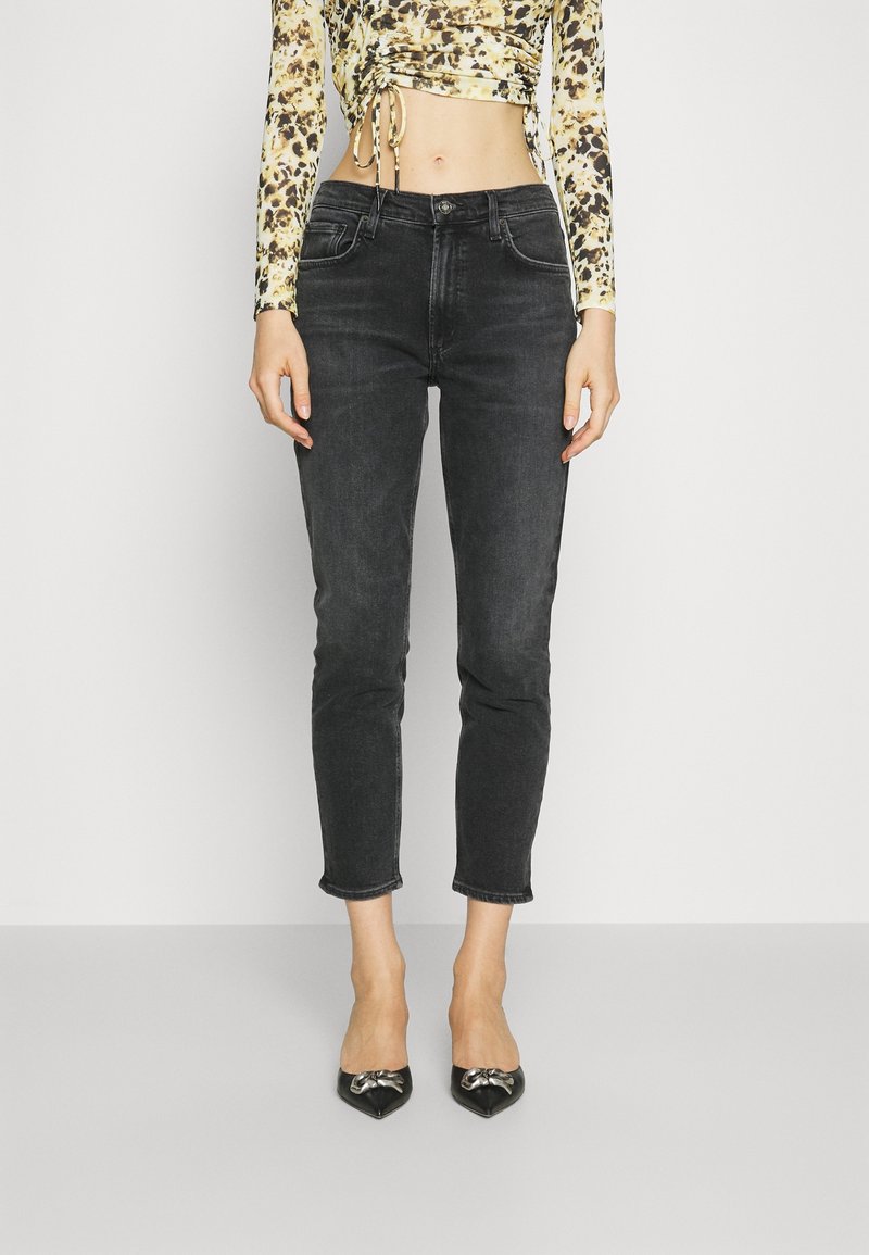 Svarta beskurna jeans med smal passform och fransad kant, kombinerade med en figurnära, mönstrad långärmad topp och spetsiga svarta klackar.