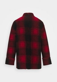 Czerwona i czarna flanelowa koszula w kratę o luźnym kroju, z długimi rękawami i kołnierzem typu zapinany na zakładkę; posiada podwinięte mankiety oraz teksturowany wzór.