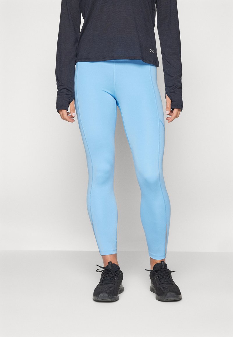 Leggings deportivos de color azul claro con una textura suave y un diseño ajustado, combinados con una camiseta de manga larga oscura y zapatillas deportivas negras.
