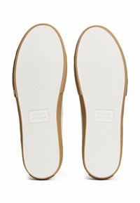 Suelas de goma blanca con superficie de agarre texturizada, acentos en color beige a lo largo de los bordes y la marca "TOMMY HILFIGER" grabada.