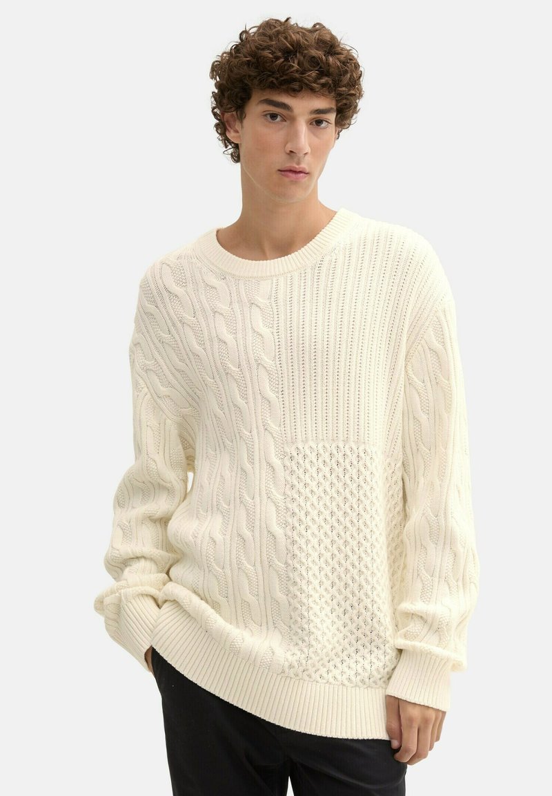 Kreemist cable-knit villane pingutus, millel on tekstuursed mustrid. Omaduseks on ümmargune kaelus ja ribitud äär. Pehme, mahukas kudum materjal lisab sooja ja visuaalset huvi.