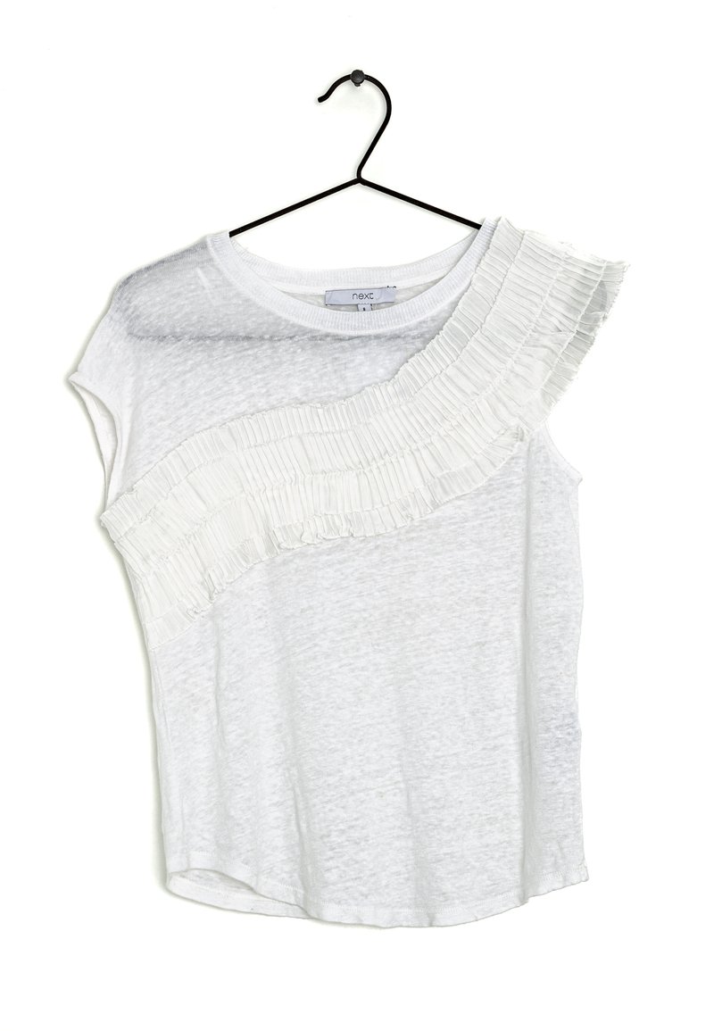 Haut à manches courtes blanc avec un détail froncé texturé et plissé le long d'une épaule. Fabriqué en tissu léger et légèrement transparent. Suspendu à un crochet noir.