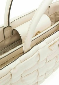 Borsa color crema con texture intrecciata, materiale in pelle, manici superiori, hardware dorato e tasca interna con zip.