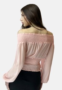 Off-the-shoulder bluse i lyserød, med smocket bodice og flagrende lange ærmer, lavet af let, struktureret stof.