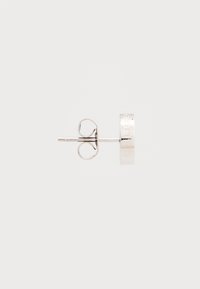 Orecchino a bottone in argento con design circolare, rifinitura lucida e dettagli incisi. Presenta un perno dritto con chiusura a farfalla.
