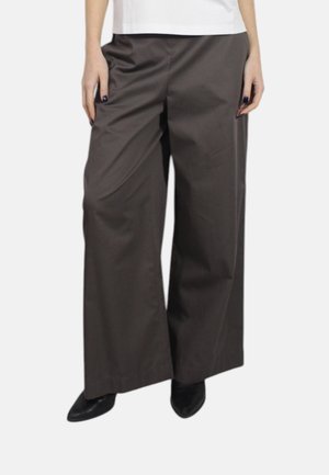Braune weit geschnittene Hose aus glattem Stoff, mit hoher Taille und seitlichen Taschen, getragen mit schwarzen Absätzen.