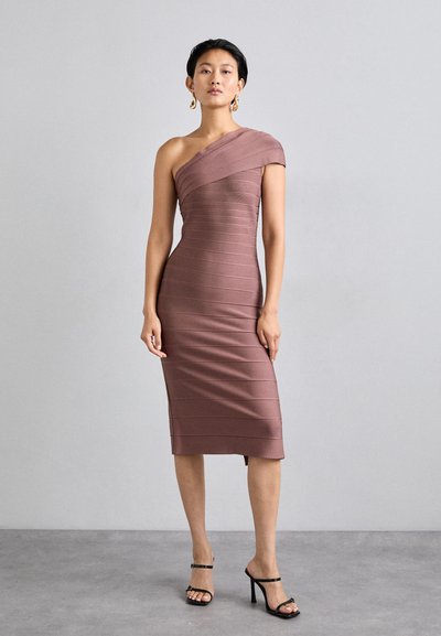 Abito bodycon malva con spalla unica. Realizzato in tessuto a coste con righe orizzontali. Lunghezza al ginocchio, con uno spacco laterale. Sandali neri con tacco.