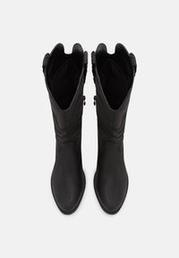 Bottes noires en cuir montant jusqu'aux genoux, avec une finition lisse, un bout arrondi et des accents tressés au sommet. La doublure intérieure est douce et texturée.