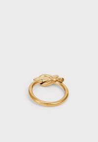 Gold-colored metal ring with a smooth finish, featuring a twisted design and a small cylindrical accent on one side.