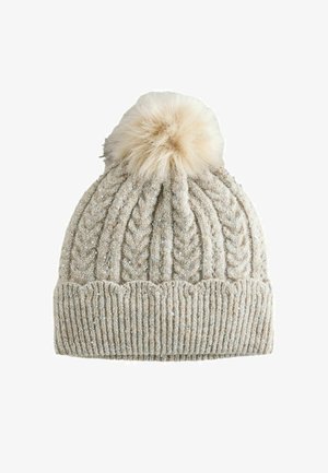 Neulepipo vaaleassa beigestä, jossa on kuviollinen palmikkoneule, ribattu reunus ja tekoturkispom pom päällä; hienosävyisiä metallinhohtoja ympäriinsä.