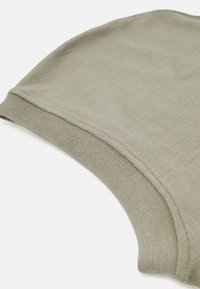 Bonnet en coton de couleur vert olive atténué, avec une texture lisse et une couronne arrondie. Présente un revers côtelé pour un ajustement confortable.