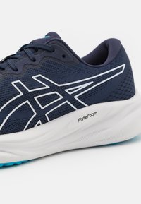 Scarpa da corsa navy con tomaia in mesh, dettagli bianchi e ammortizzazione FlyteFoam. Presenta una suola testurizzata per la presa e una forma snella.