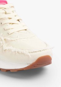 Sneaker in tela color crema con bordi sfrangiati e suola in gomma. Presenta una linguetta rosa, lacci piatti e un upper in tessuto testurizzato.