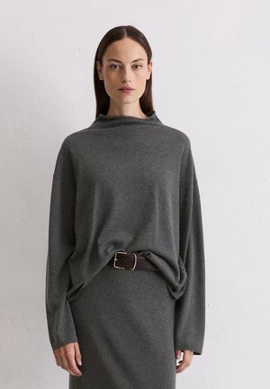 Grijze, oversized trui met een kraag, lange mouwen en een ontspannen pasvorm, gecombineerd met een bruine riem met een gouden gesp.