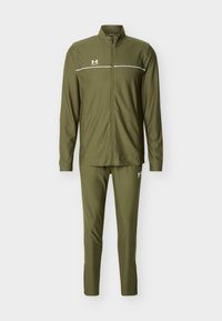 Veste de survêtement zippée olive verte et pantalon slim assorti avec logos Under Armour blancs et une fine bande blanche horizontale sur la poitrine.