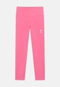 Ružové legíny vyrobené z elastického materiálu, s vysokým pásom a malým bielym logom Disney a Adidas na spodnej časti nohy.