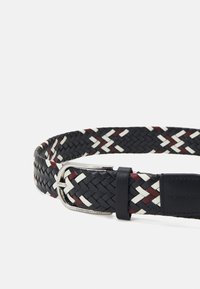 Cintura intrecciata in nero, bianco e bordeaux, con una fibbia in metallo color argento e una patta in pelle liscia per la regolazione.