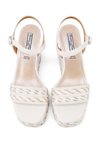 Infradito bianchi in pelle con dettagli in fibra naturale intrecciata e fibbia regolabile alla caviglia. Texture liscia con design a punta quadrata.