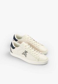 Cream leather sneakers with navy accents, featuring a logo with a skull and crossbones, round toe, and flat lace-up design.