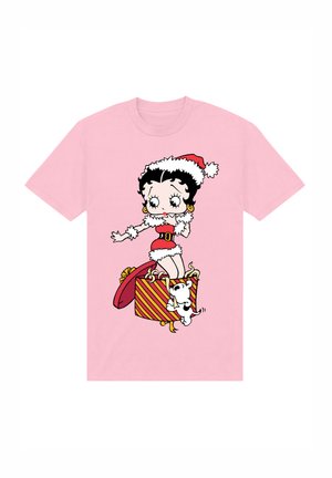 Lyserød bomulds t-shirt med en grafik af en karakter iført en julesweater på en stribet gaveæske, mens en lille hvid hund hopper ved siden af hende.