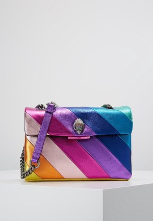 Sac à bandoulière en cuir aux couleurs de l'arc-en-ciel avec des rayures diagonales, une bandoulière chaîne argentée et un fermoir en forme de coquillage sur un socle blanc.