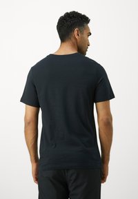 Sort bomulds t-shirt med rund hals og korte ærmer, der har en glat tekstur og en afslappet pasform, set bagfra.