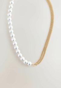 Náhrdelník s prameňom lesklých bielych falošných perál spárovaných s textúrovaným zlatým reťazcom, vytvárajúcim kontrast materiálov a štýlov.