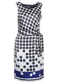 Robe sans manches en satin blanc avec de grands pois navy, une taille nouée et un ourlet navy accentué de petits pois blancs.