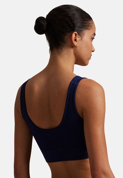 Tmavě modrá sportovní podprsenka na míru s širokými ramínky, hladkou texturou a žebrovaným vzorem. Má zaoblený zadní design pro pohodlí a podporu.