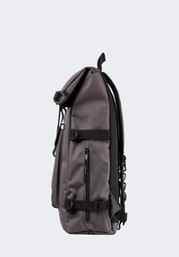 Mochila de tela gris con un diseño aerodinámico, que cuenta con correas ajustables, múltiples bolsillos con cremallera y una superficie texturizada.
