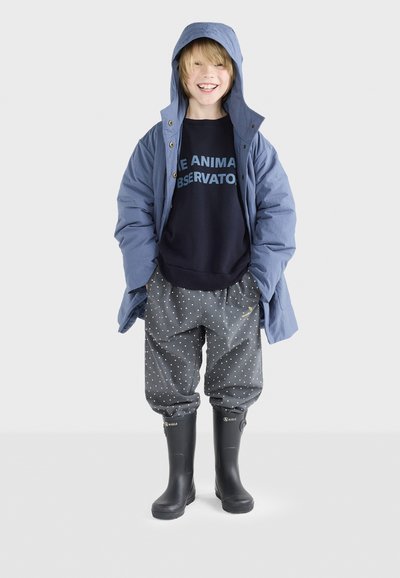 Blauer wasserdichter Mantel, dunkelgrauer Pullover mit blauer Schrift, graue Polka-Dot-Hosen und schwarze Gummistiefel. Verfügt über eine Kapuze und eine lockere Passform.