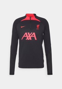 Musta pitkähihainen treenipaita puoliveto-ristikoilla, punaiset yksityiskohdat, Liverpool FC:n logo ja AXA-logo; teksturoitu kuvio hihoissa.