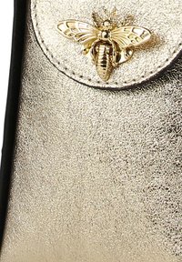 Metallisch goldene Handtasche mit strukturierter Oberfläche, ausgestattet mit einer dekorativen Bienenförmigen Hardware an der Klappe und schwarzem Rand.