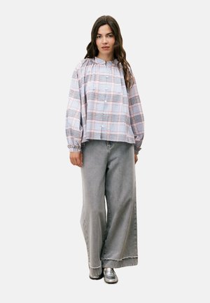 Chemise en flanelle à carreaux bleus, roses et blancs ; coupe ample avec encolure froncée et manches longues. Associée à un pantalon en denim gris à jambes larges.