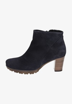 Mörk marinblå mocka ankelsko med rund tå, texturerad gummisula och staplad träklack. Utrustad med en siddragkedja för enkel på- och avtagning.