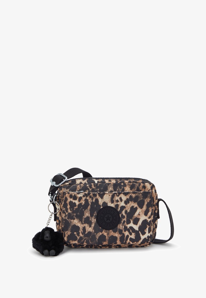 Torebka crossbody w panterkę z czarnym okrągłym logo, z zamkiem błyskawicznym oraz futrzanym breloczkiem z małpką przymocowanym do boku.
