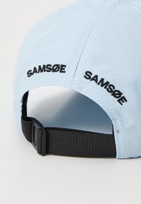 Light blue cap with black “SAM Sø” embroidery, featuring a curved brim and an adjustable black strap at the back for sizing.