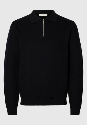 Suéter negro de punto con cuello con cremallera, puños y dobladillo acanalados. Presenta un patrón texturizado y un diseño de ajuste relajado.