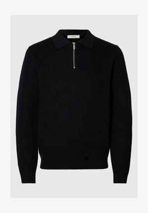 Svart stickad tröja med dragkedjeförsedd krage, ribbade muddar och fåll. Har ett strukturerat mönster och en avslappnad passform.