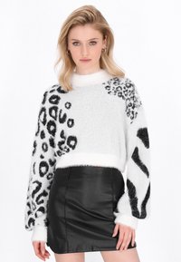 Gekürzter, flauschiger Pullover in Weiß mit schwarzen Tierdruckmustern; verfügt über lange, voluminöse Ärmel und einen weichen, geribbelten Ausschnitt.