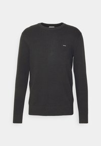 Maglione grigio scuro a maniche lunghe con design a coste testurizzato. Collo rotondo, polsini aderenti e piccolo logo del marchio sul petto. Taglio classico.