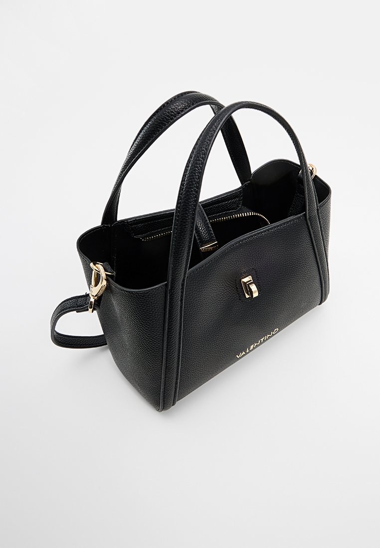 Bolso negro texturizado con dobles asas, cierre de cremallera, herrajes dorados y logo en la parte frontal. Forma rectangular compacta.