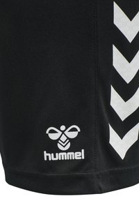 Schwarze Shorts mit glatter Textur, die ein großes weißes Chevron-Muster auf einer Seite und ein weißes Logo mit einem Bienenentwurf am Saum aufweisen.