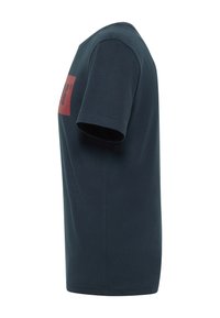 Tamsiai mėlynas trumpomis rankovėmis marškinėliai, pagaminti iš medvilnės, su raudonu stačiakampiu logotipu priekyje, klasikinio apvalaus kaklo ir tiesaus kirpimo.